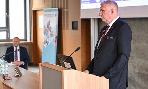 Wiceminister Zdrowia Wojciech Konieczny stoi przy mównicy, wygłaszając przemówienie.