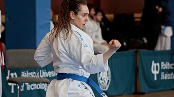 Kobieta w białym stroju karate wykonuje kopnięcie.